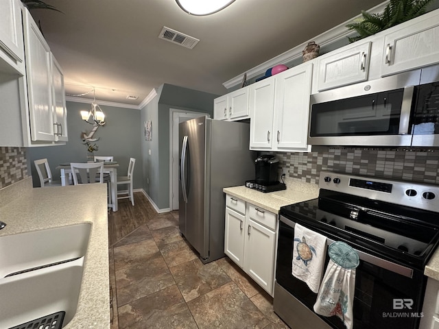 1517 Regency Rd Unit 121, Gulf Shores, AL 36542 - kitchen with stainless steel appliances, tasteful backsplash, white cabinets, light countertops, and a chandelier
