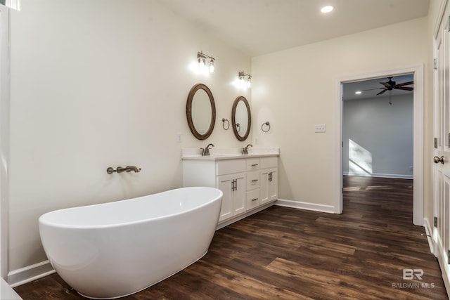 bathroom with wood-type flooring, vanity, ceiling fan, and a tub