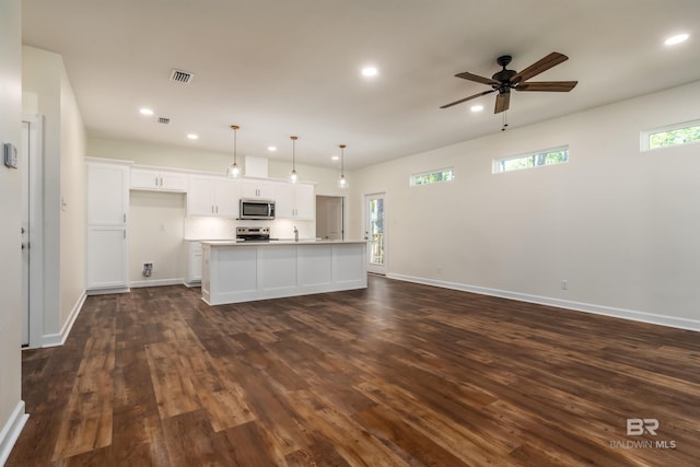 kitchen featuring a kitchen island with sink, white cabinets, dark hardwood / wood-style floors, decorative light fixtures, and stainless steel appliances