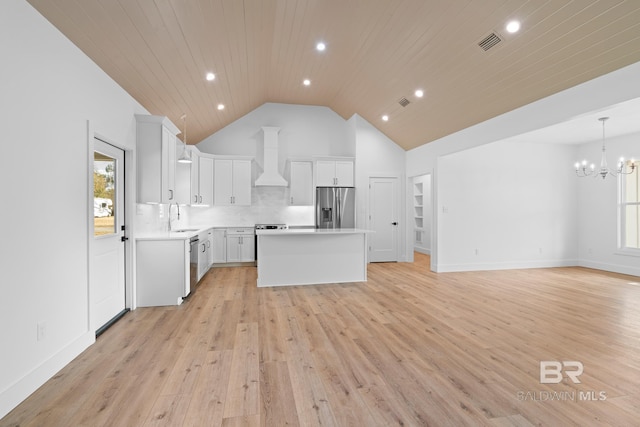 kitchen with sink, white cabinetry, stainless steel appliances, a kitchen island, and wall chimney exhaust hood