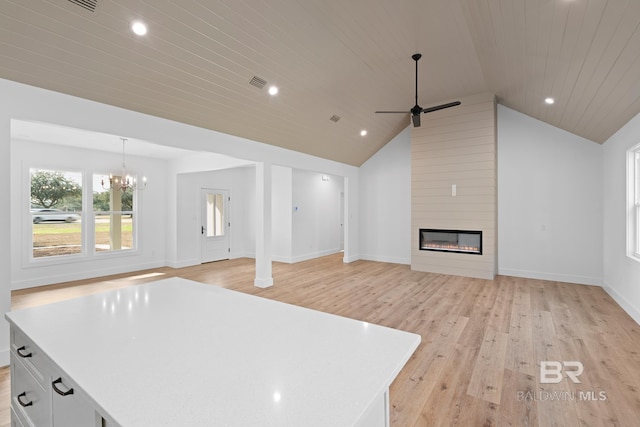 unfurnished living room featuring wood ceiling, vaulted ceiling, light wood-type flooring, a large fireplace, and ceiling fan with notable chandelier