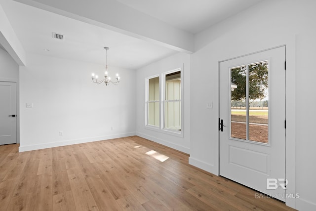 unfurnished dining area featuring light wood-type flooring and an inviting chandelier