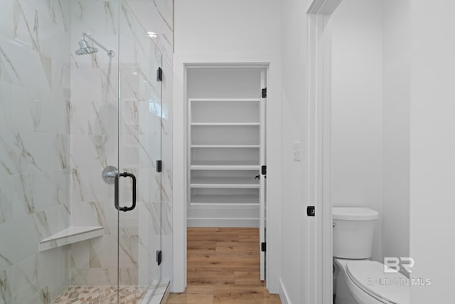 bathroom with a shower with shower door, toilet, and wood-type flooring