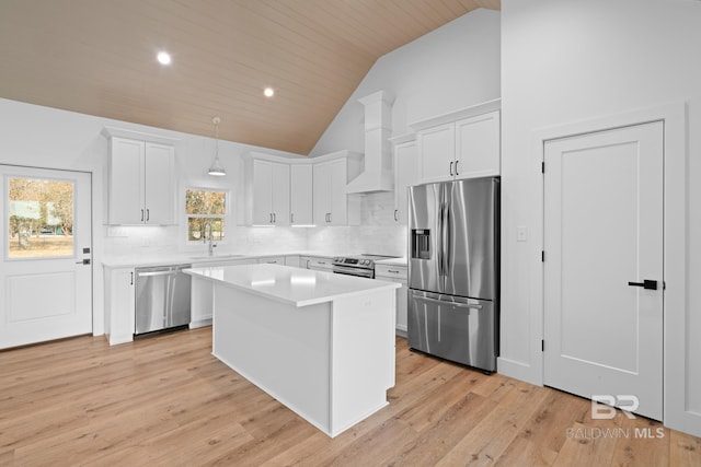 kitchen with appliances with stainless steel finishes, decorative light fixtures, white cabinetry, sink, and a center island