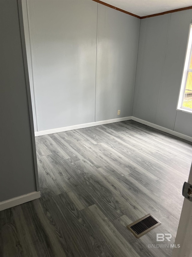 unfurnished room with ornamental molding, wood finished floors, visible vents, and baseboards