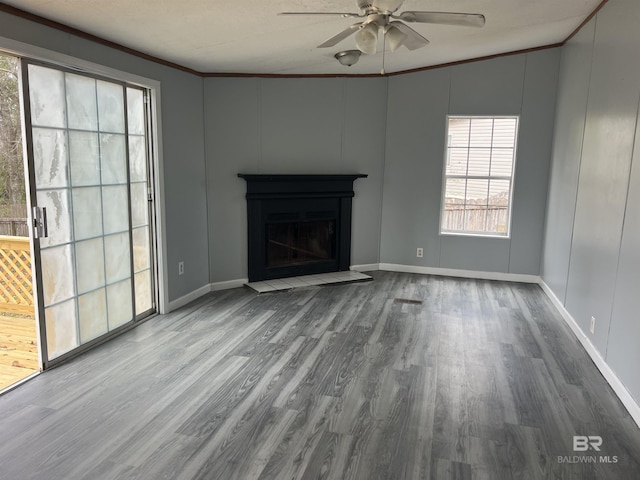 unfurnished living room with a fireplace with raised hearth, ceiling fan, wood finished floors, and crown molding