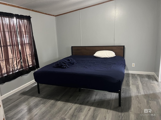 bedroom with a textured ceiling, wood finished floors, and baseboards