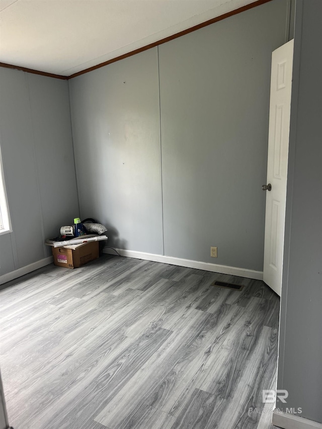 spare room with baseboards, wood finished floors, and crown molding