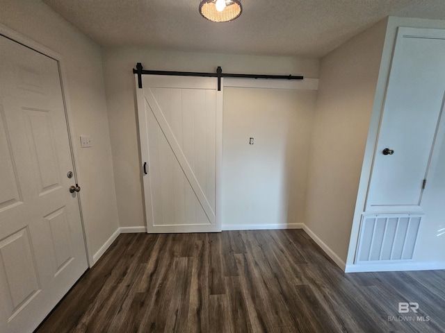 524 Linda Ln, Saraland, AL 36571 - unfurnished bedroom with dark wood finished floors, a barn door, baseboards, and a textured ceiling