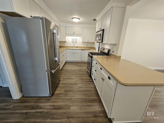 524 Linda Ln, Saraland, AL 36571 - kitchen with stainless steel appliances, dark wood-type flooring, a peninsula, light countertops, and white cabinets
