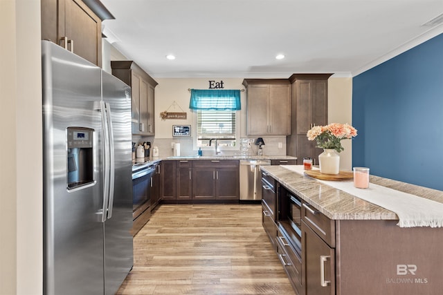 kitchen featuring stainless steel appliances, light wood-style floors, backsplash, and dark brown cabinetry