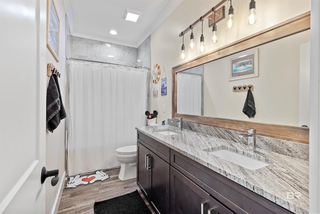 full bathroom featuring double vanity, wood finished floors, a sink, and toilet