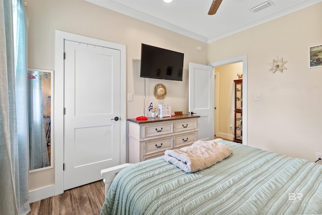 bedroom featuring ceiling fan, visible vents, dark wood finished floors, and crown molding