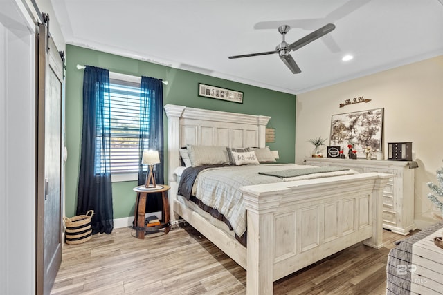 bedroom with baseboards, ceiling fan, light wood finished floors, and a barn door