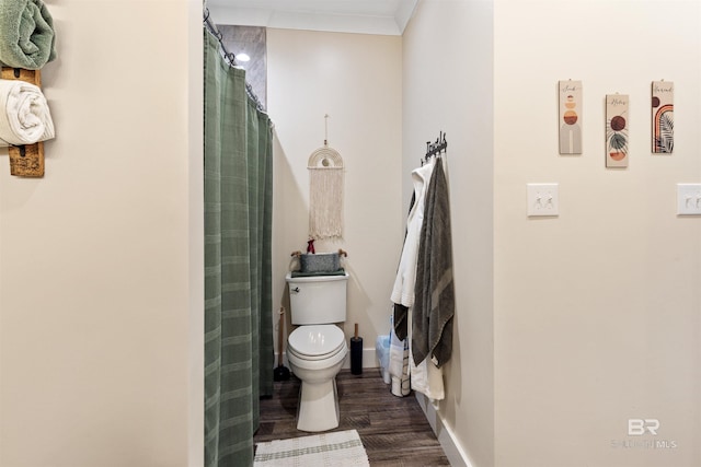 bathroom featuring a shower with shower curtain, toilet, ornamental molding, wood finished floors, and baseboards