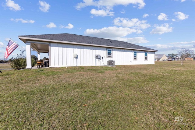 rear view of property with board and batten siding, a yard, a patio, and central air condition unit