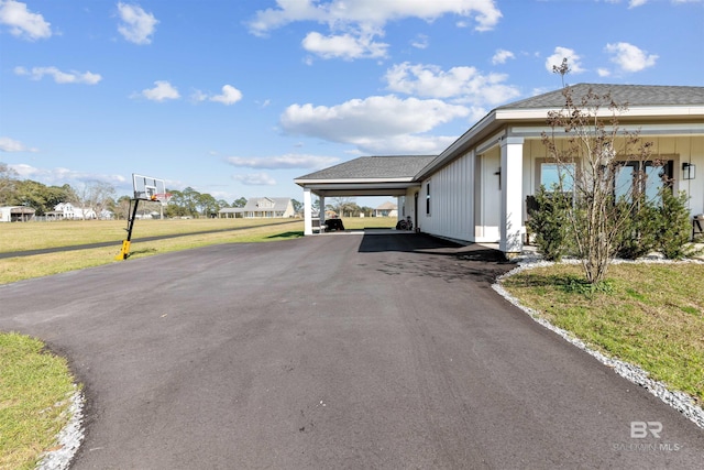 view of side of home with driveway, an attached carport, and a yard