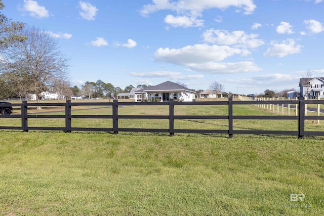 view of gate with a rural view, fence, and a lawn