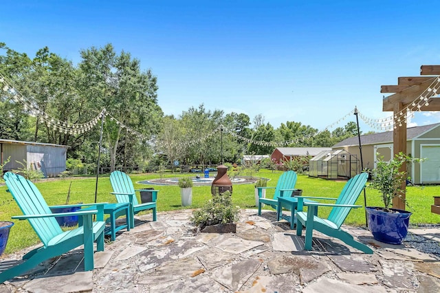 view of patio featuring a fire pit, an outdoor structure, an exterior structure, and fence