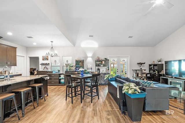 kitchen with french doors, a breakfast bar area, light wood-type flooring, and light stone countertops