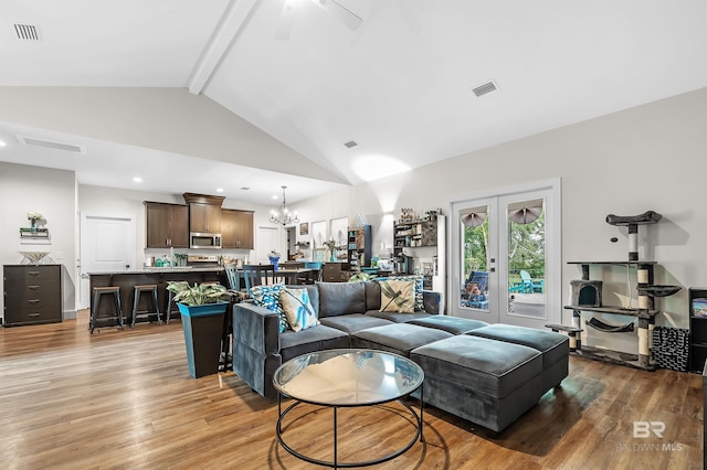 living room with beam ceiling, ceiling fan with notable chandelier, hardwood / wood-style flooring, and high vaulted ceiling