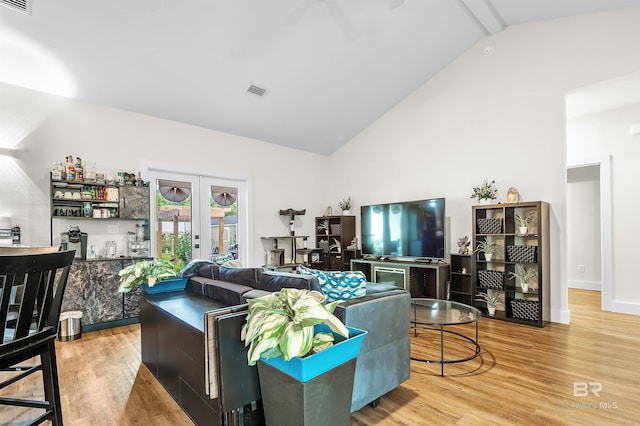 living room featuring light hardwood / wood-style flooring, beamed ceiling, french doors, and high vaulted ceiling