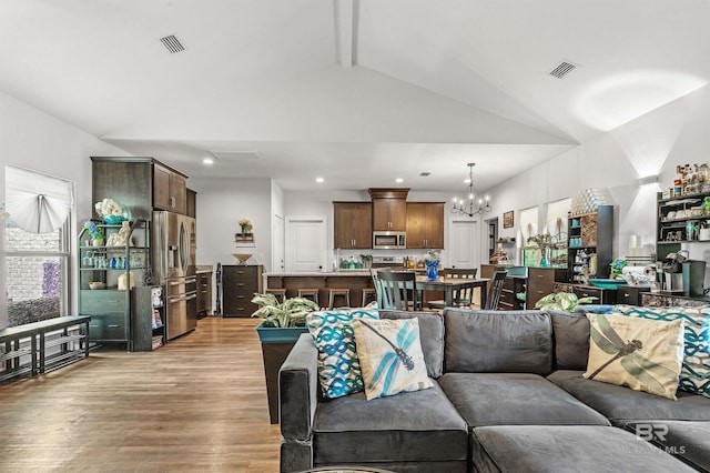 living area with light wood-style floors, visible vents, vaulted ceiling with beams, and a notable chandelier