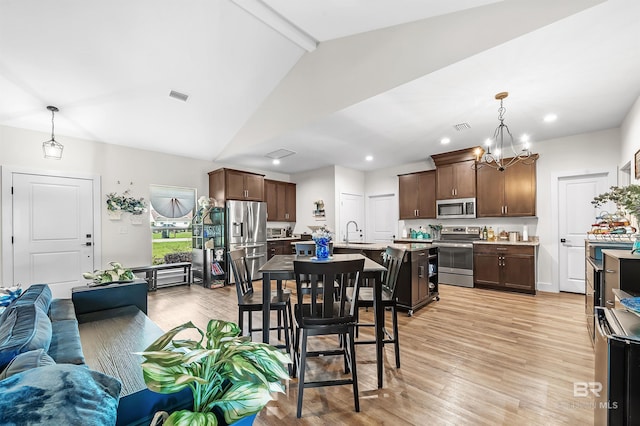 dining area featuring light wood-type flooring, visible vents, and beamed ceiling