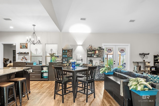 dining area with a chandelier, french doors, and light wood-type flooring