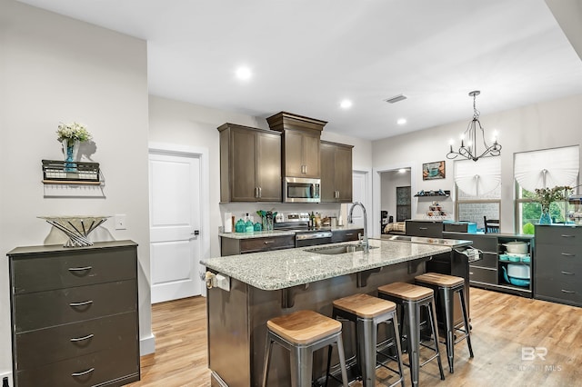 kitchen with a breakfast bar area, visible vents, appliances with stainless steel finishes, light wood-style floors, and a sink