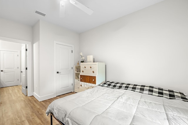 bedroom featuring baseboards, light wood-style flooring, visible vents, and a ceiling fan