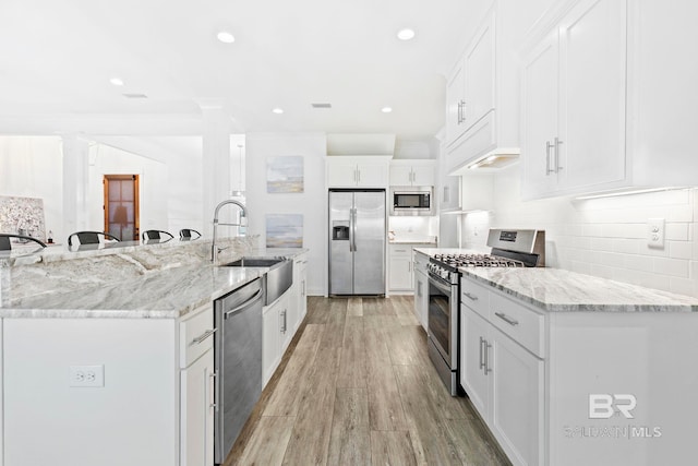 kitchen with light stone counters, white cabinets, and appliances with stainless steel finishes