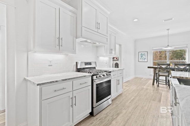 kitchen with hanging light fixtures, gas stove, white cabinets, and light stone counters