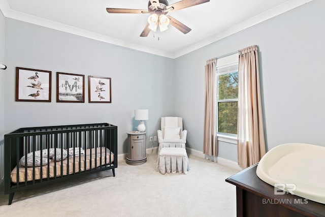 bedroom featuring ornamental molding, a nursery area, light carpet, and ceiling fan