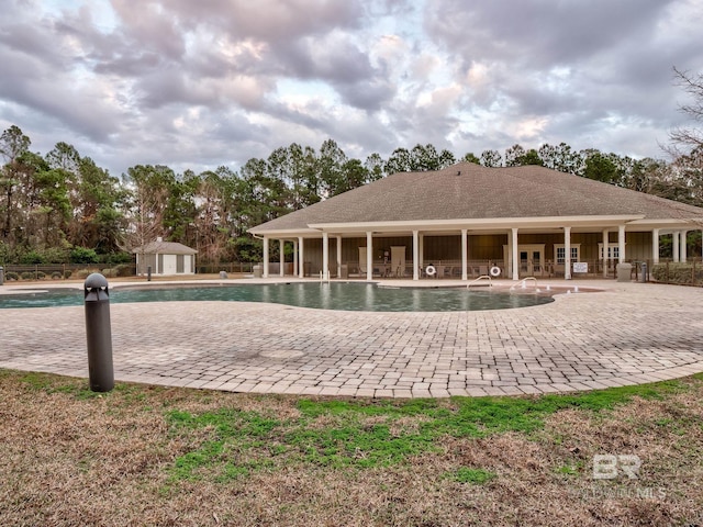 back of property with an outdoor structure, a community pool, and a patio area