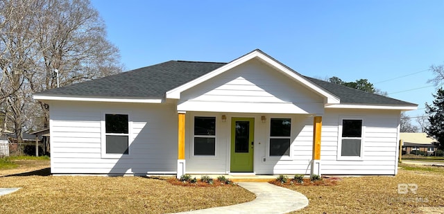 view of front of house with covered porch, a shingled roof, and a front yard