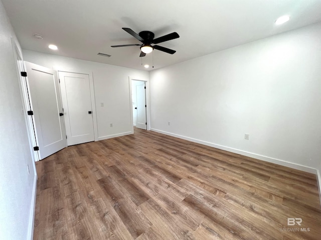 unfurnished bedroom featuring recessed lighting, wood finished floors, a ceiling fan, visible vents, and baseboards