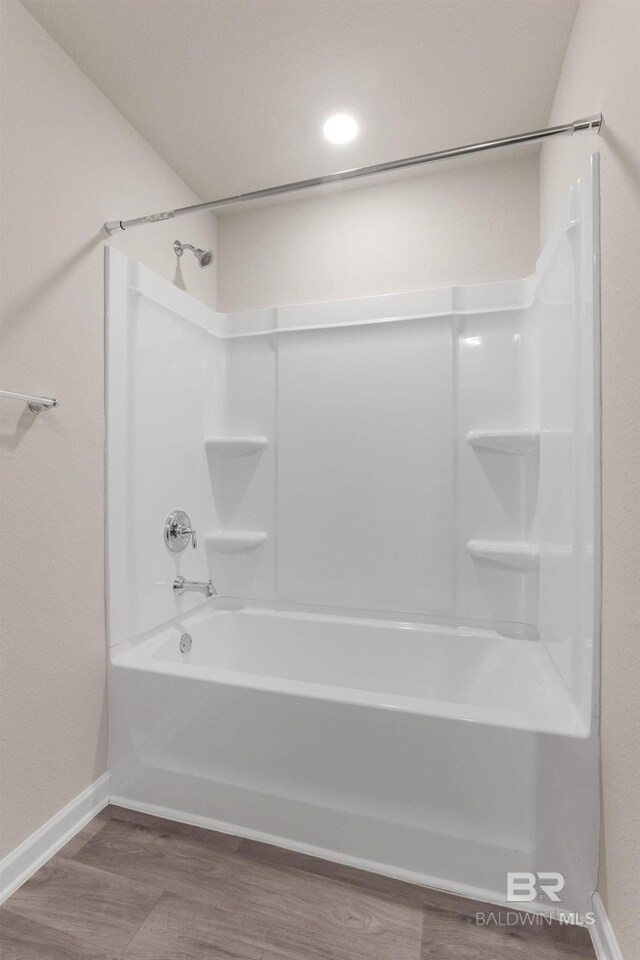 bathroom featuring  shower combination, wood finished floors, and baseboards