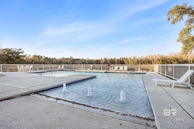 community pool with a patio area and fence