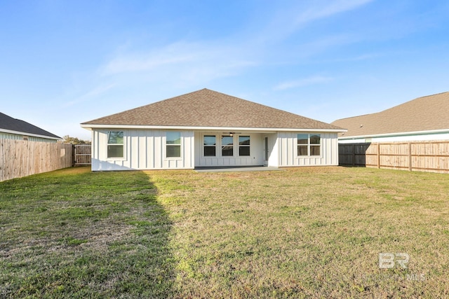 rear view of property with roof with shingles, board and batten siding, a fenced backyard, and a lawn