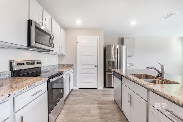 kitchen featuring stainless steel appliances, visible vents, a sink, and light stone countertops