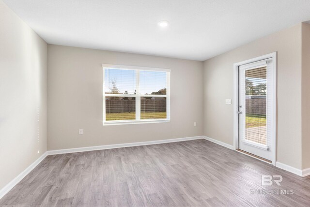 spare room featuring light wood-style flooring and baseboards