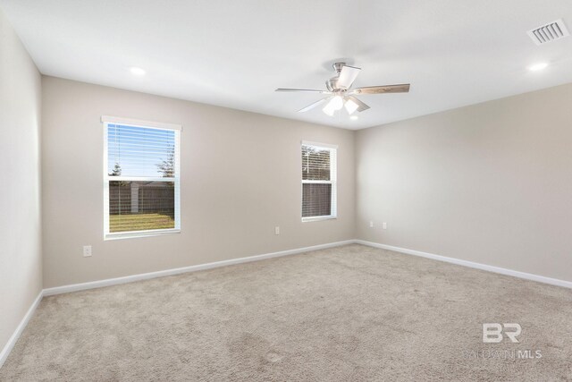 carpeted spare room featuring visible vents, ceiling fan, and baseboards