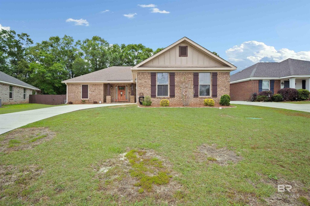 single story home featuring a front yard, driveway, board and batten siding, and brick siding