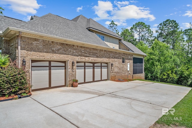 10128 Alder Ave, Spanish Fort, AL 36527 - view of home's exterior featuring concrete driveway, brick siding, roof with shingles, a garage, and board and batten siding