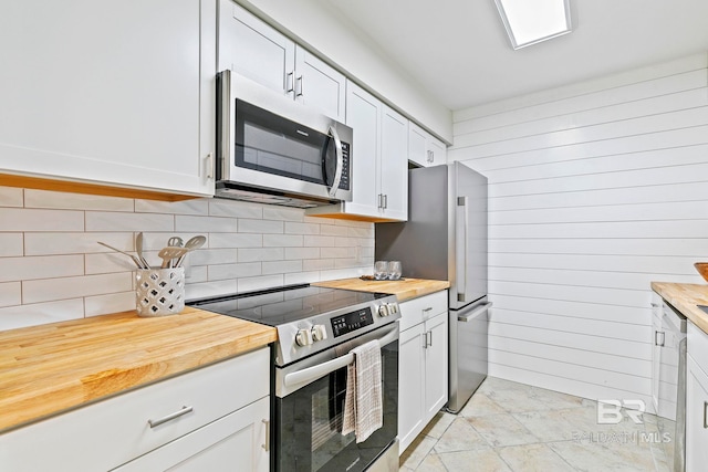 kitchen featuring wooden counters, wooden walls, decorative backsplash, white cabinets, and appliances with stainless steel finishes