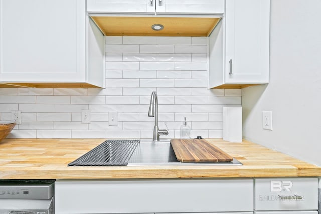 kitchen with stainless steel dishwasher, decorative backsplash, and white cabinetry