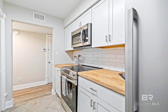 kitchen with white cabinets, stainless steel appliances, decorative backsplash, light wood-type flooring, and wood counters