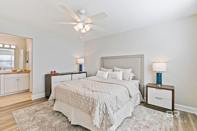 bedroom with light hardwood / wood-style floors, ensuite bath, sink, and ceiling fan