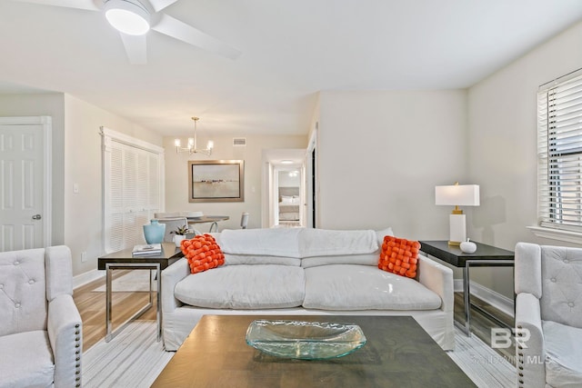 living room with ceiling fan with notable chandelier and hardwood / wood-style flooring